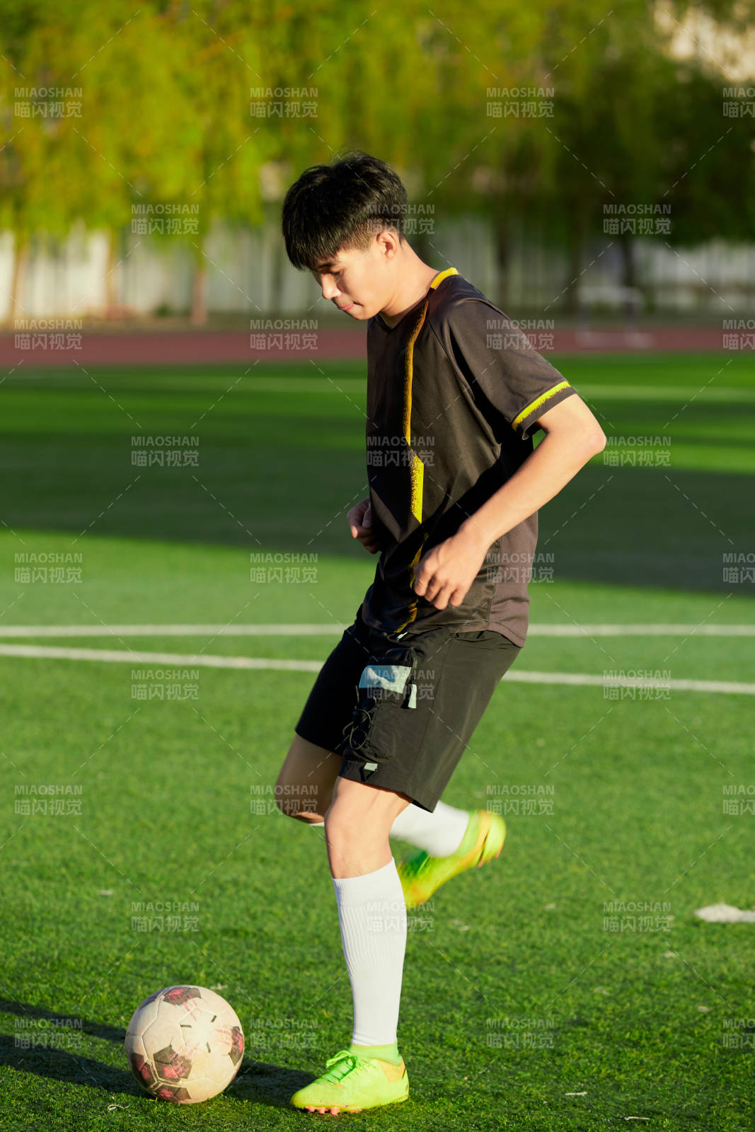 户外足球场上踢足球的运动员图片