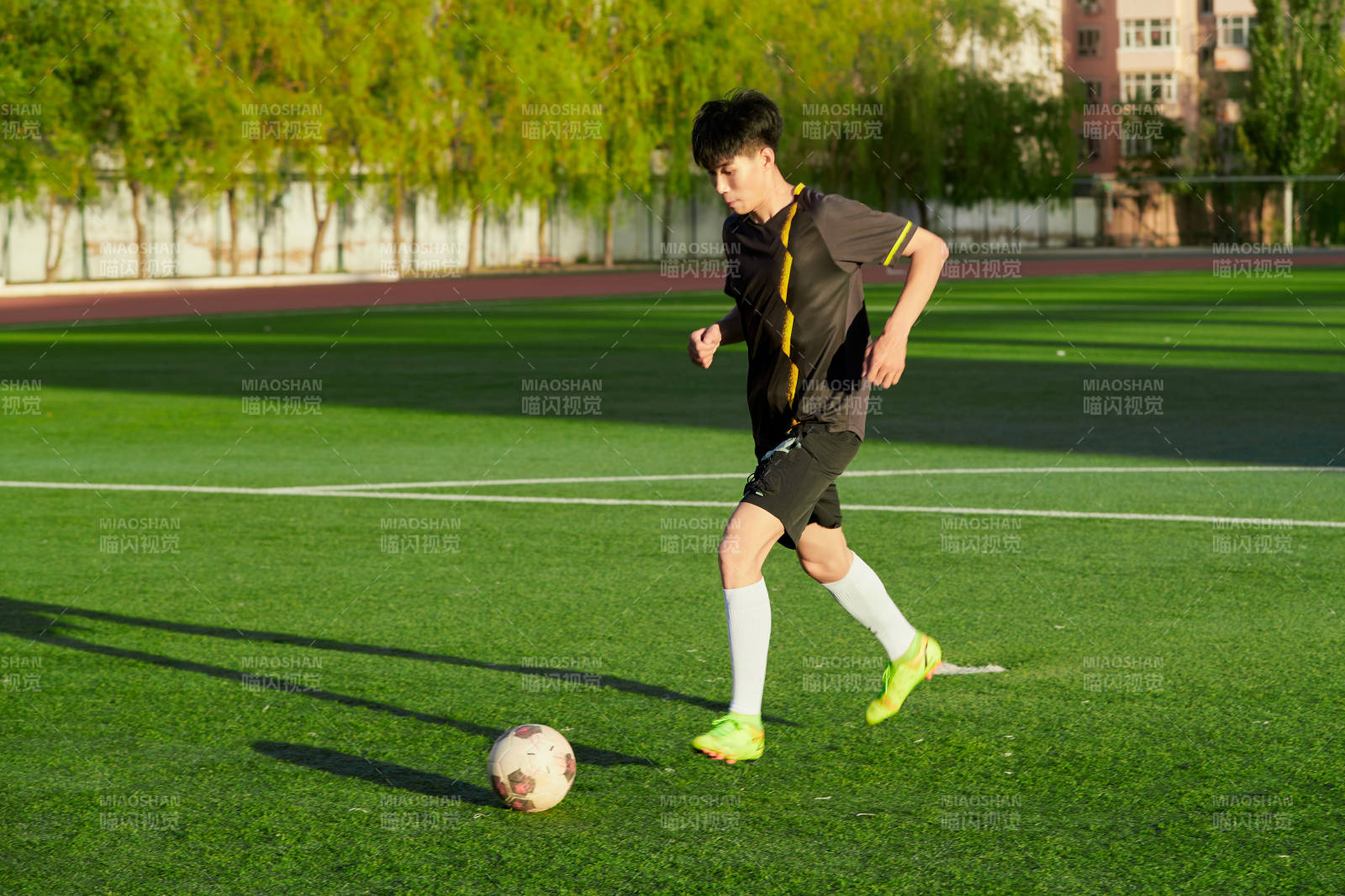 户外足球场上踢足球的运动员图片