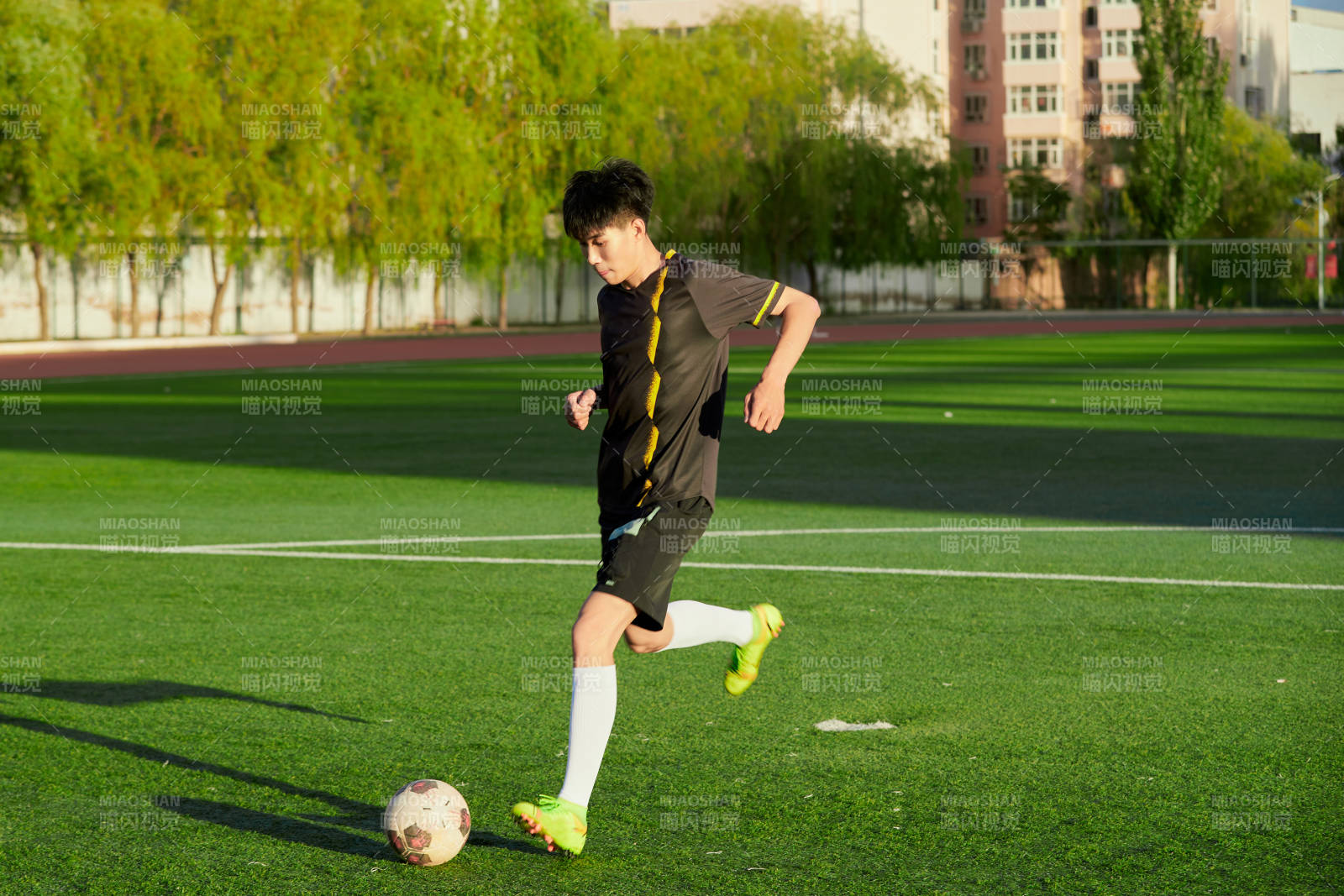 户外足球场上踢足球的运动员图片