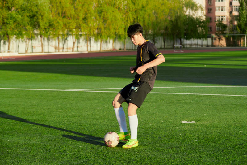 户外足球场上踢足球的运动员图片