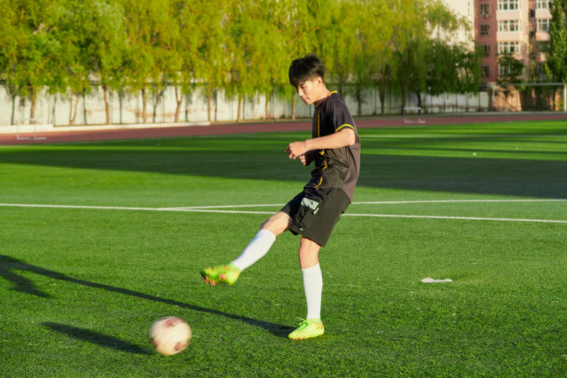 户外足球场上踢足球的运动员图片