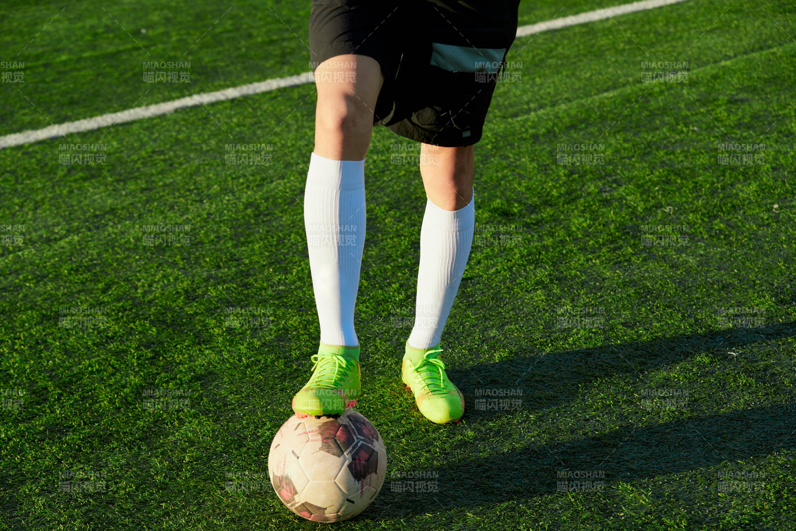 户外足球场上踢足球的运动员图片