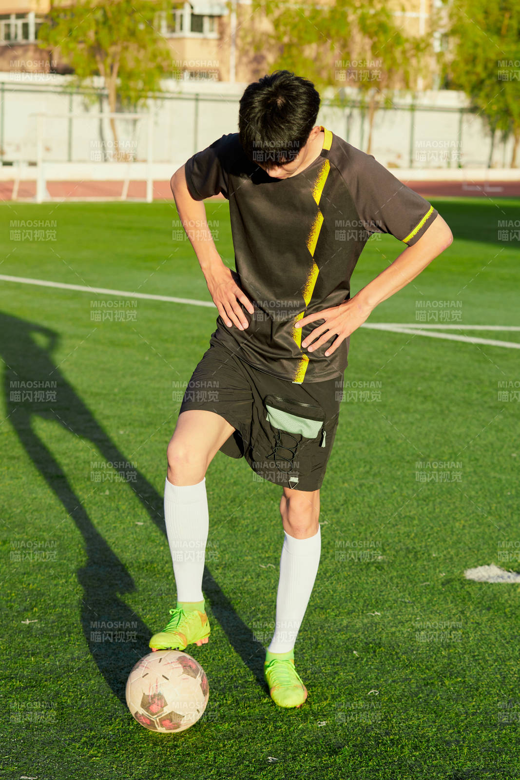户外足球场上踢足球的运动员图片