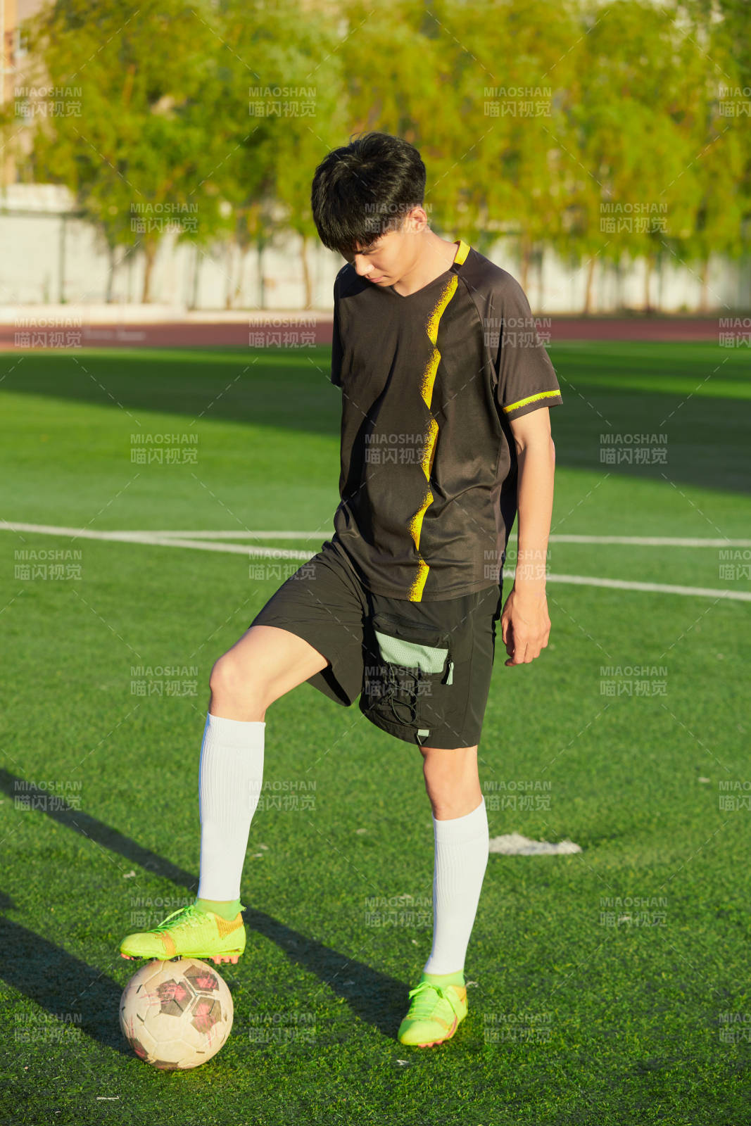 户外足球场上踢足球的运动员图片