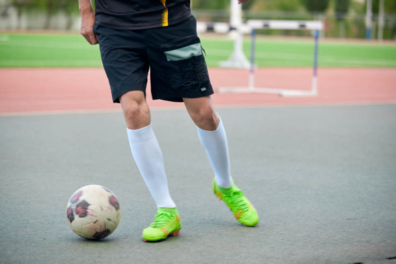 户外足球场上踢足球的运动员图片