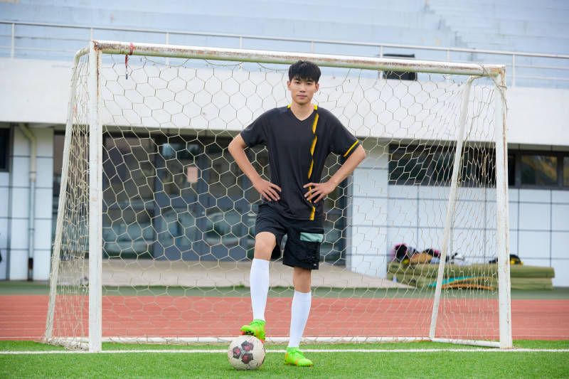 户外足球场上踢足球的运动员图片