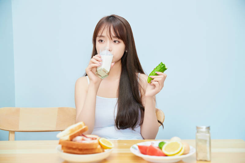 美丽的少女在餐桌前吃早餐图片