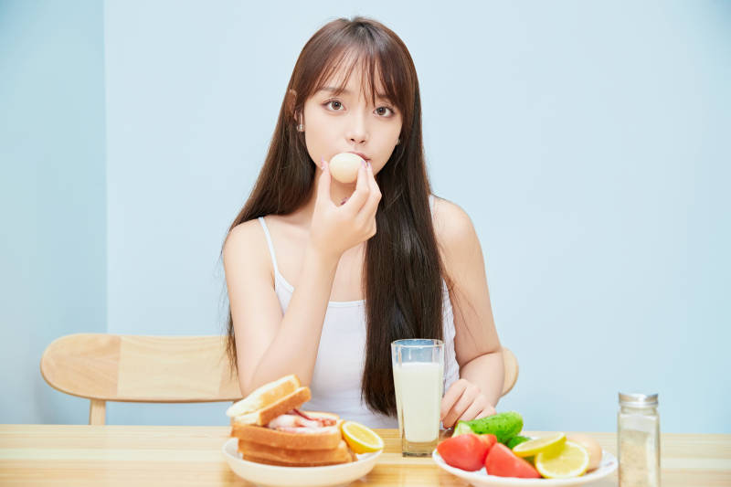 美丽的少女在餐桌前吃早餐图片