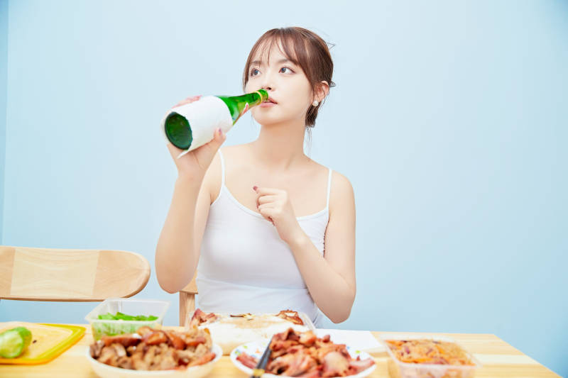 在餐桌前吃午餐喝白酒的亚洲少女图片