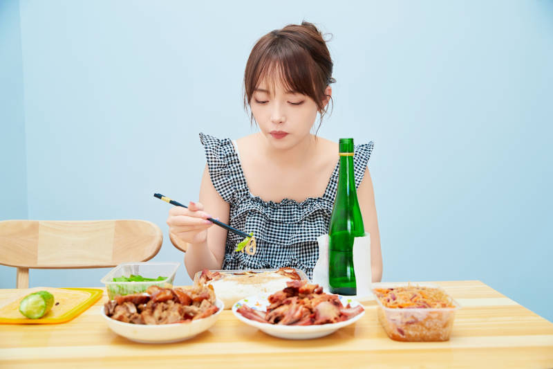 在餐桌前吃午餐喝白酒的亚洲少女图片