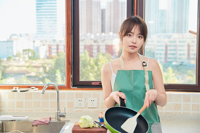 在厨房下厨做饭的年轻亚洲女性图片