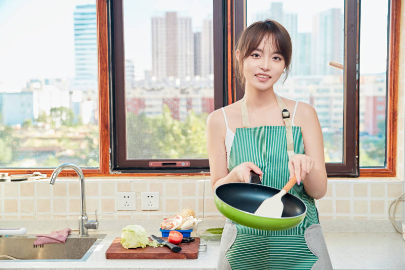 在厨房下厨做饭的年轻亚洲女性图片