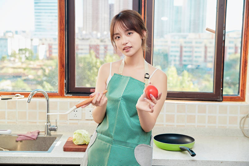 在厨房下厨做饭的年轻亚洲女性图片