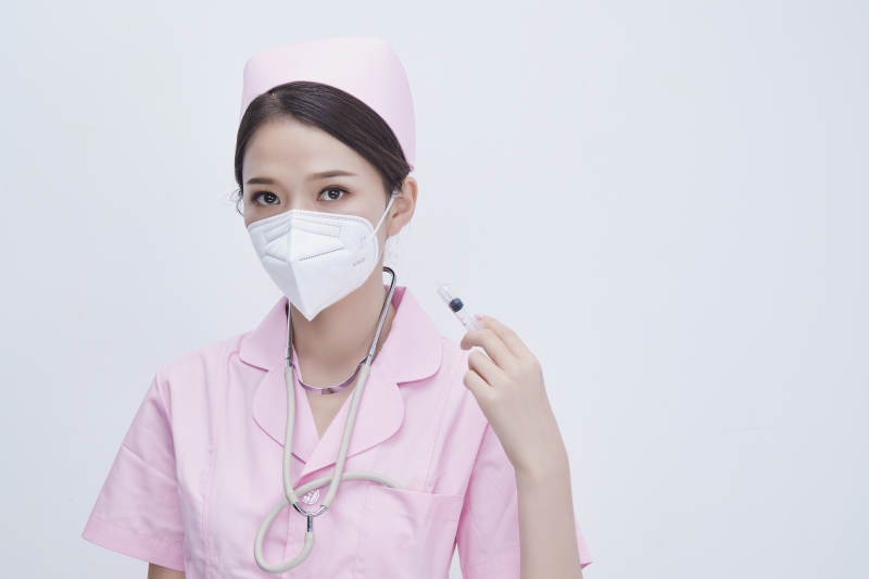 穿护士服戴听诊器口罩手执针筒的年轻女护士图片