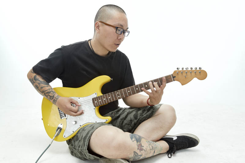 手持电吉他展示演奏的亚洲男性摇滚乐手人像图片