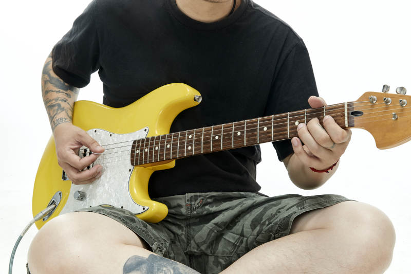 示范演奏摇滚电吉他的亚洲男性乐手人像局部特写图片