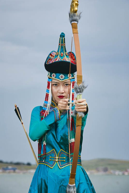 草原湖畔身穿蒙古族饰手持弓箭的蒙族少女图片