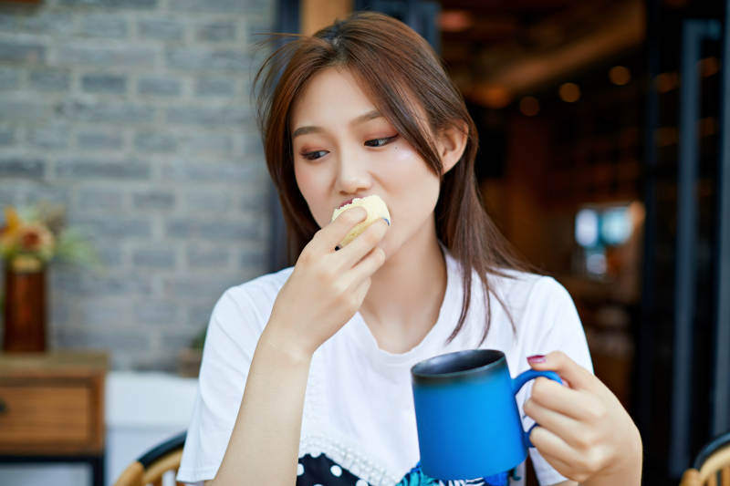 坐在咖啡图书馆吃东西的可爱少女图片