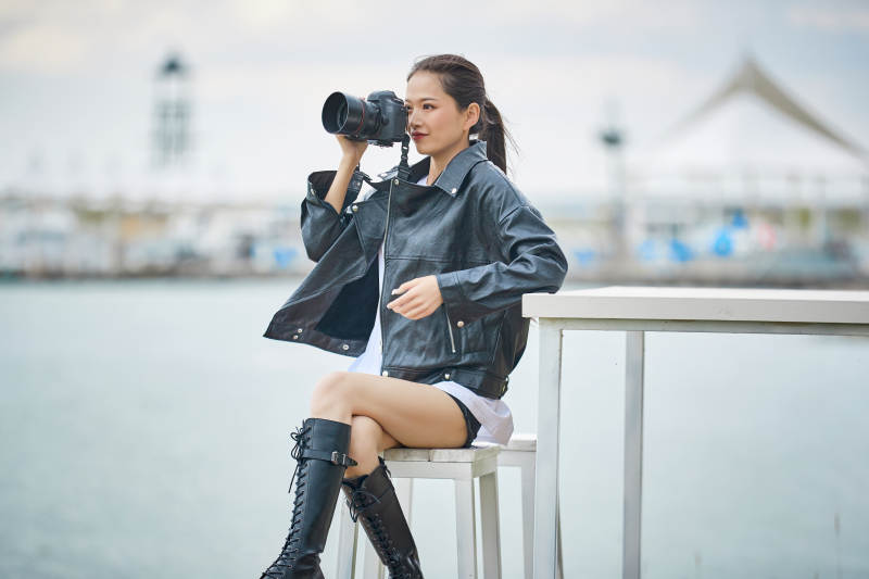 户外湖畔进行拍摄的亚洲青年女性摄影师图片