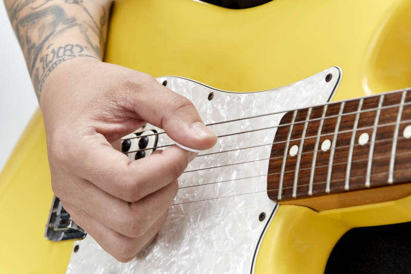 示范演奏摇滚电吉他的亚洲男性乐手人像局部特写图片