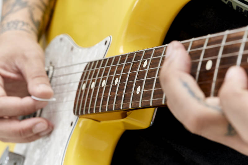 示范演奏摇滚电吉他的亚洲男性乐手人像局部特写图片