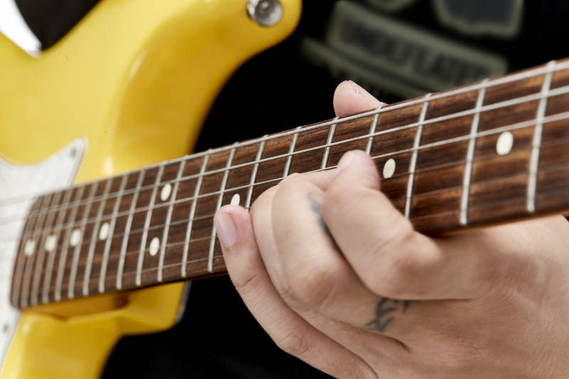 示范演奏摇滚电吉他的亚洲男性乐手人像局部特写图片