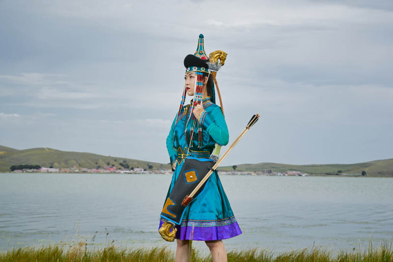 草原湖畔身穿蒙古族饰手持弓箭的蒙族少女图片