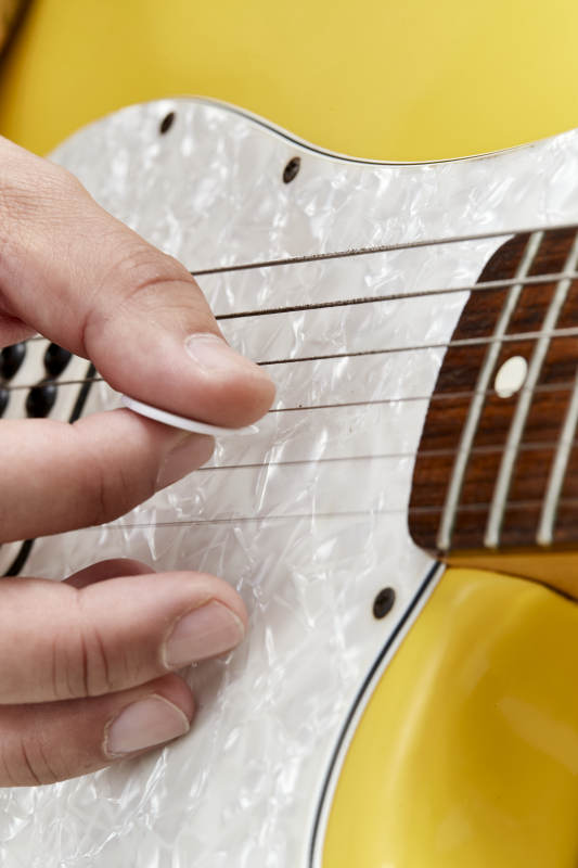 示范演奏摇滚电吉他的亚洲男性乐手人像局部特写图片