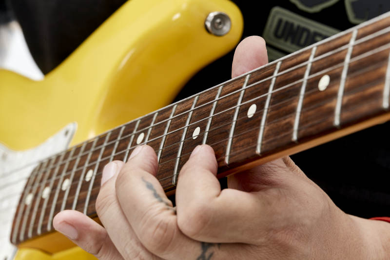 示范演奏摇滚电吉他的亚洲男性乐手人像局部特写图片