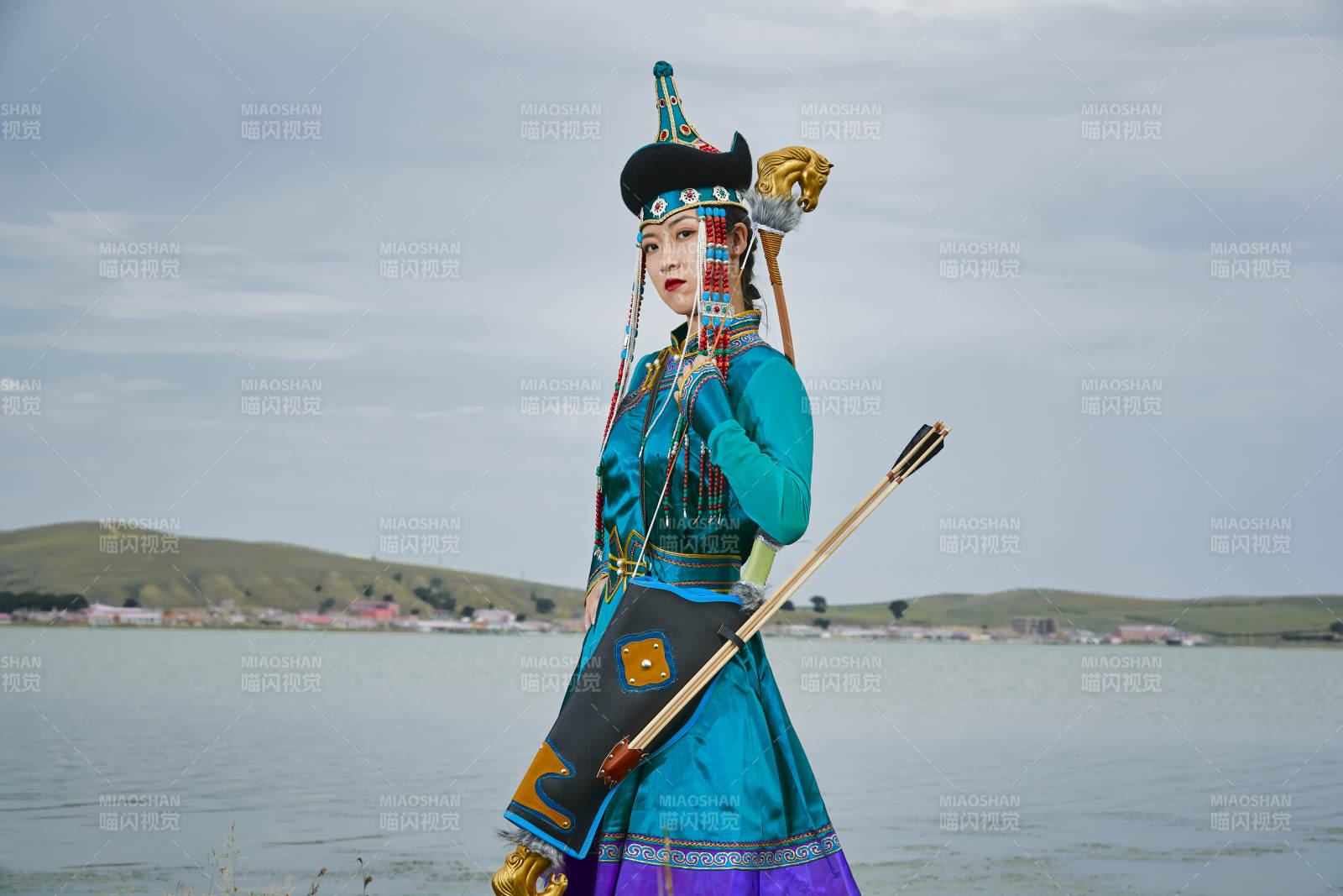 草原湖畔身穿蒙古族饰手持弓箭的蒙族少女图片
