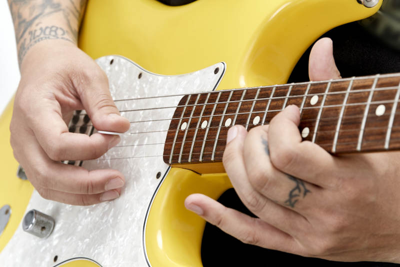 示范演奏摇滚电吉他的亚洲男性乐手人像局部特写图片