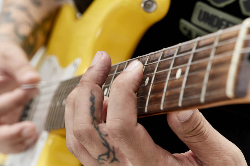 示范演奏摇滚电吉他的亚洲男性乐手人像局部特写图片