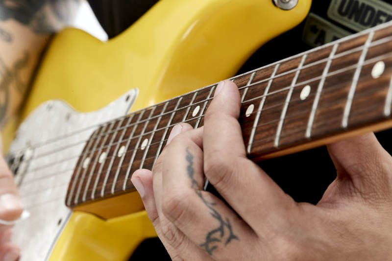 示范演奏摇滚电吉他的亚洲男性乐手人像局部特写图片