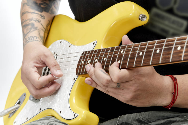 示范演奏摇滚电吉他的亚洲男性乐手人像局部特写图片