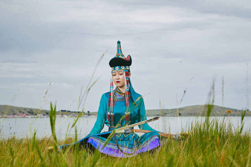 草原湖畔身穿蒙古族饰手持弓箭的蒙族少女图片