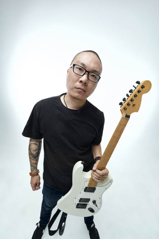 手持电吉他展示演奏的亚洲男性摇滚乐手人像图片