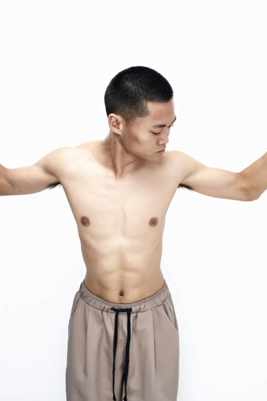 白色背景下展示健身预备拉伸动作的亚洲男性图片