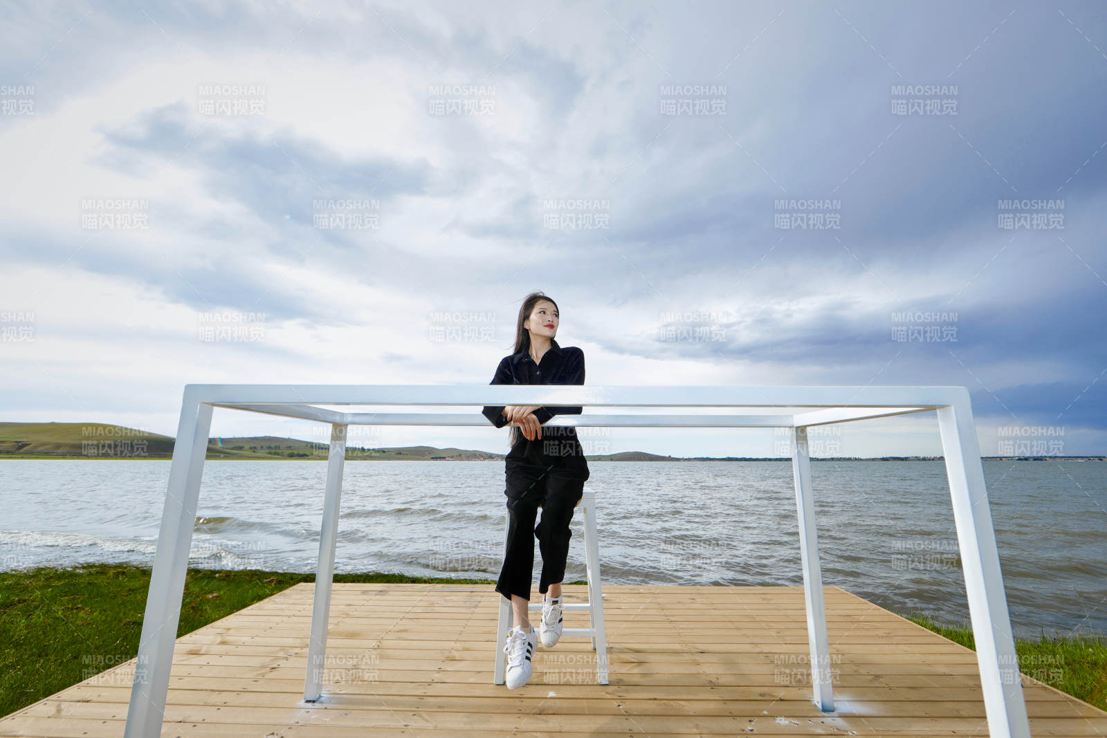 悠闲的坐在美丽湖岸码头的长发少女图片