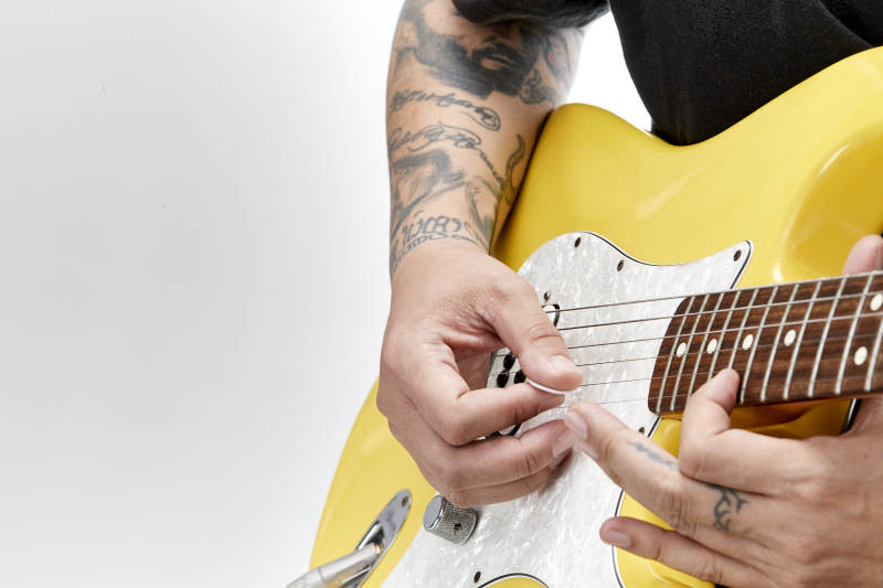 示范演奏摇滚电吉他的亚洲男性乐手人像局部特写图片