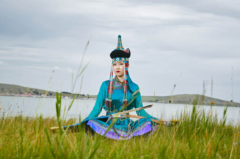 草原湖畔身穿蒙古族饰手持弓箭的蒙族少女图片