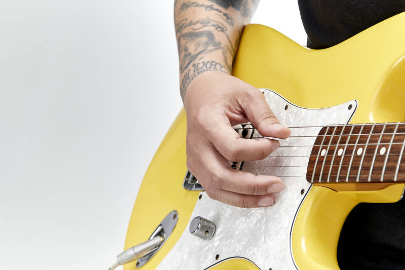 示范演奏摇滚电吉他的亚洲男性乐手人像局部特写图片