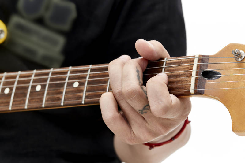 示范演奏摇滚电吉他的亚洲男性乐手人像局部特写图片