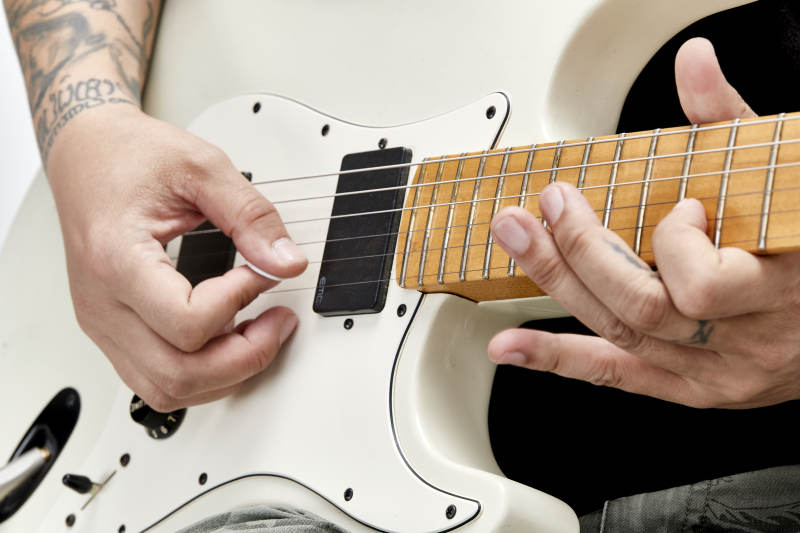 示范演奏摇滚电吉他的亚洲男性乐手人像局部特写图片