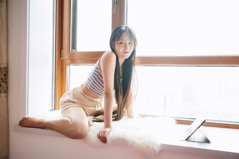 躺在舒适的飘窗上听音乐追剧的亚洲少女图片