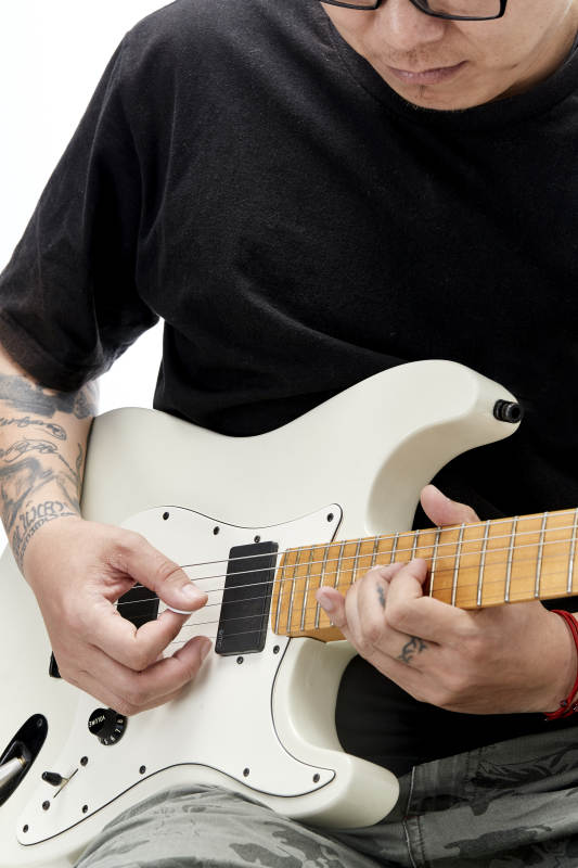 示范演奏摇滚电吉他的亚洲男性乐手人像局部特写图片