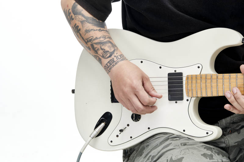 示范演奏摇滚电吉他的亚洲男性乐手人像局部特写图片