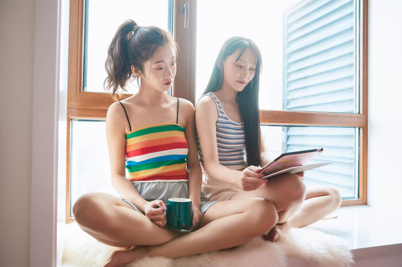 午后坐在飘窗上追剧休息的闺蜜少女图片