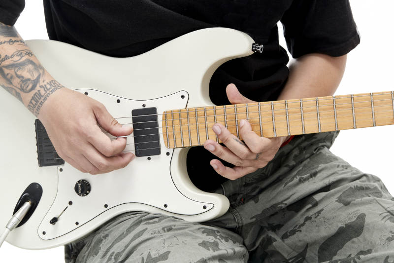 示范演奏摇滚电吉他的亚洲男性乐手人像局部特写图片