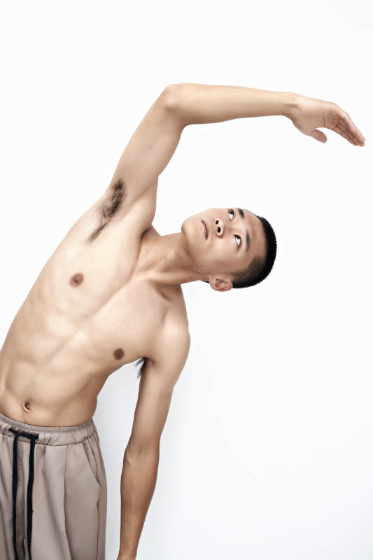 白色背景下展示健身预备拉伸动作的亚洲男性图片