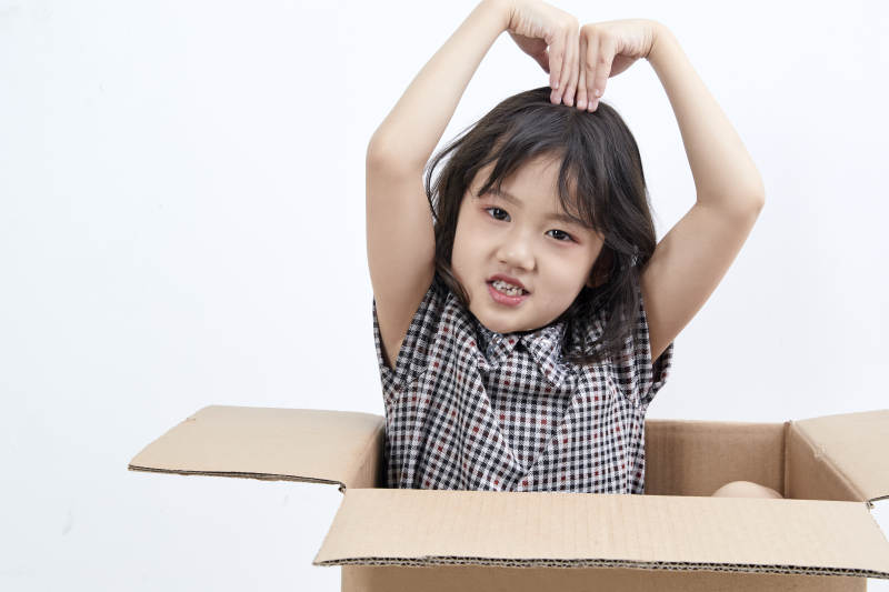 躲在纸箱中玩耍的调皮可爱亚洲小女孩儿童图片